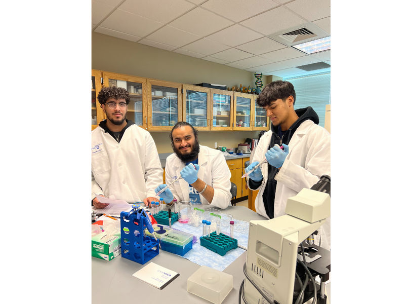 三位男性生物学家在使用实验室设备，面带微笑 